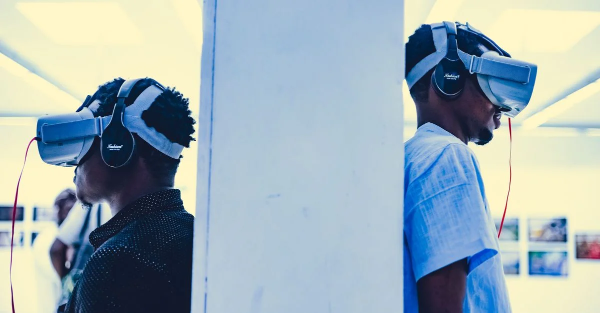 Deux adultes portant des casques VR dans un cadre d'exposition intérieur.